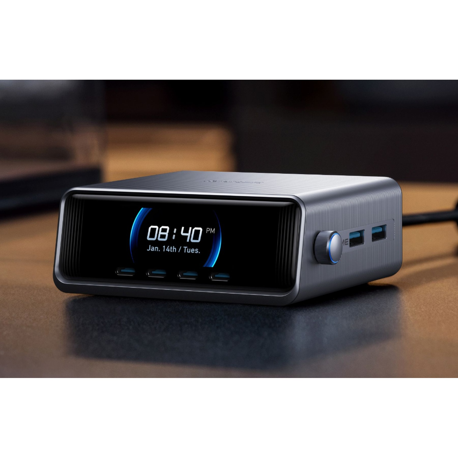 Un orologio digitale argentato mostra le 08:40, con il 14 gennaio/martedì. Ha porte USB e una manopola. Lo sfondo è sfocato.