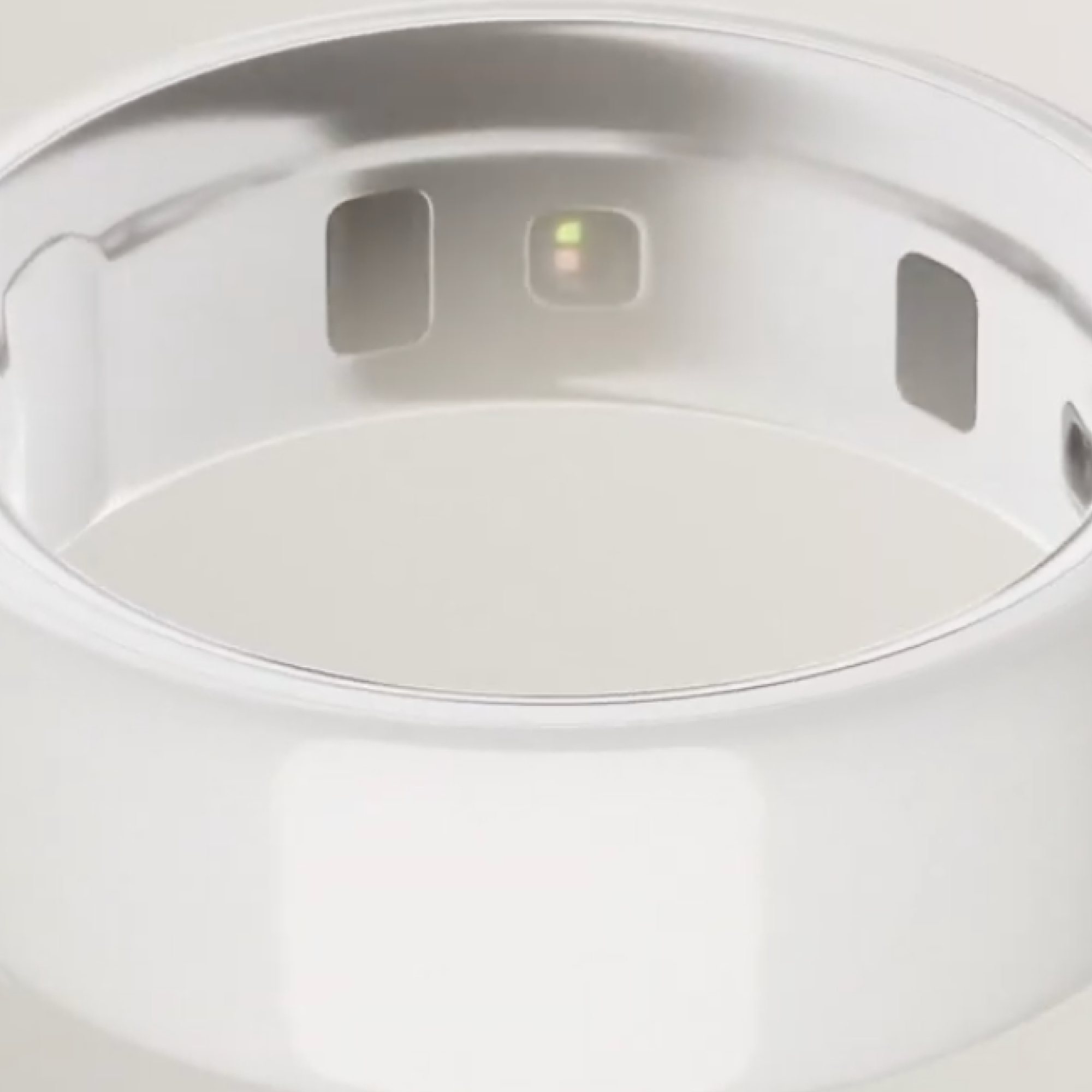 Primo piano di un anello intelligente argentato con tre aperture rettangolari. L'anello ha una superficie liscia e lucida.