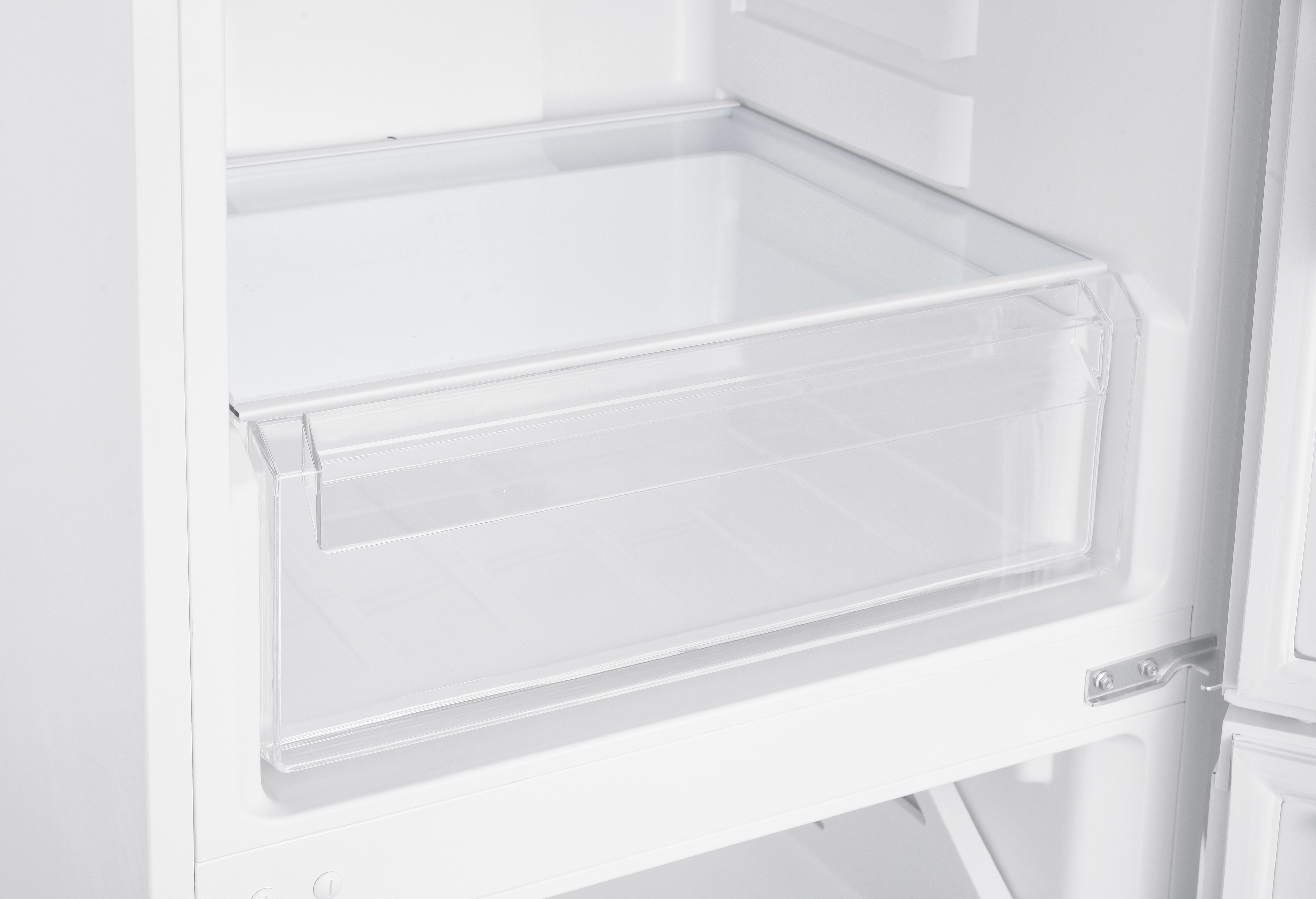 Wnętrze białej lodówki. Przezroczysta plastikowa szuflada jest częściowo wysunięta.
