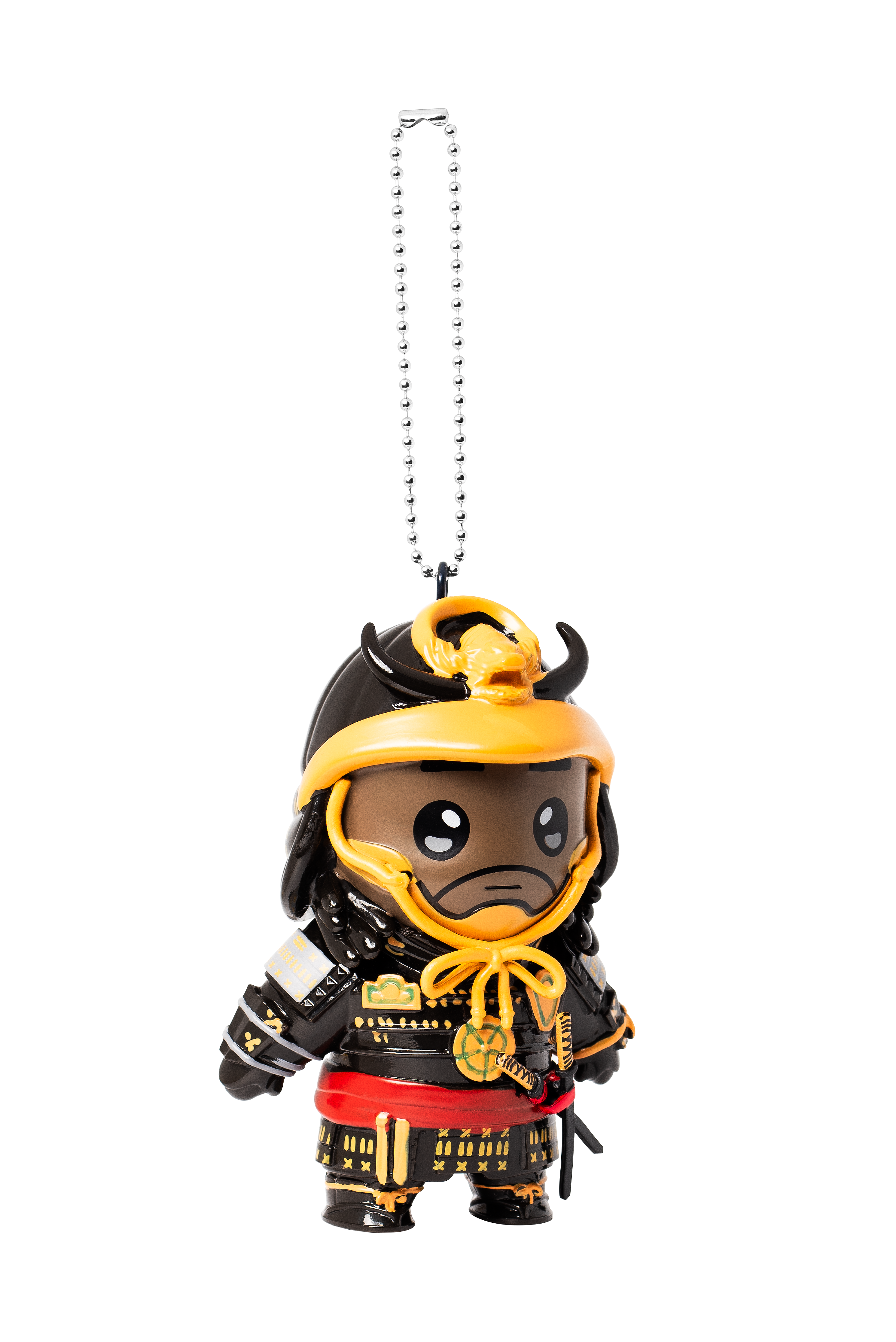 Figurka samuraja z czarną zbroją i żółtymi akcentami wisi na srebrnym łańcuchu na białym tle.