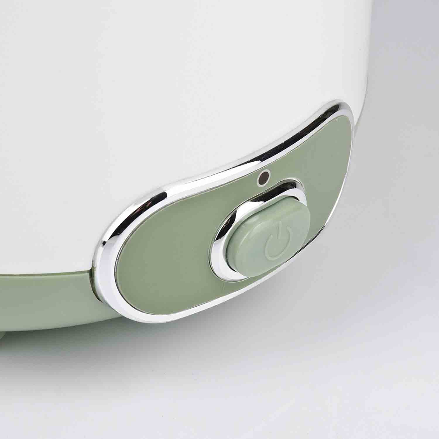 Primo piano di un elettrodomestico bianco e verde. È visibile un pulsante verde con un simbolo di accensione, circondato da un bordo argentato.