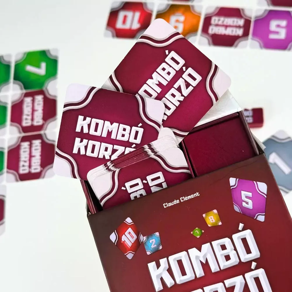 A 'Kombó Korzó' játéknak doboza kártyákkal. A kártyák és a doboz bordó színűek. Más számos kártyák szétszórva.