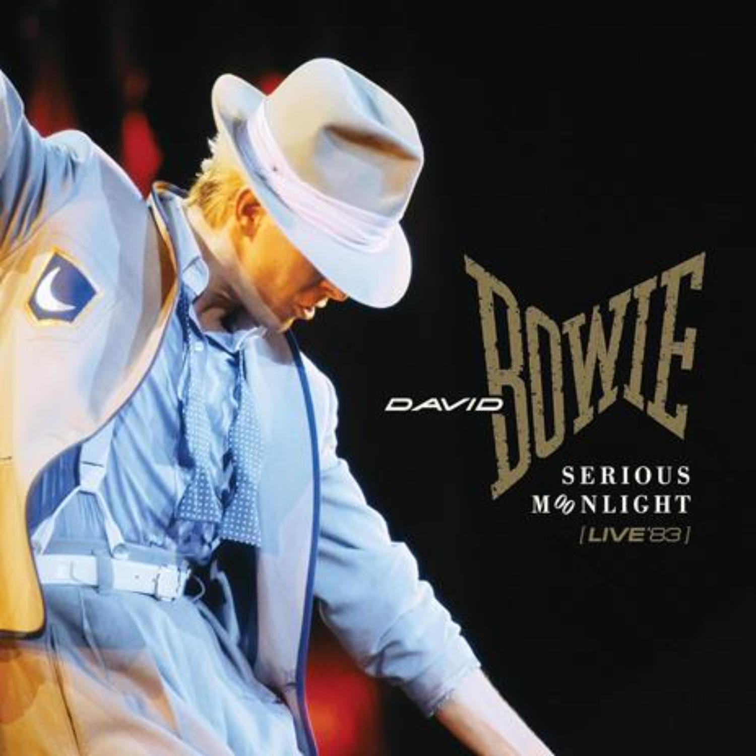 David Bowie in lichtblauw pak en hoed op het podium. Bowie-logo en tekst 'Serious Moonlight' op zwarte achtergrond.