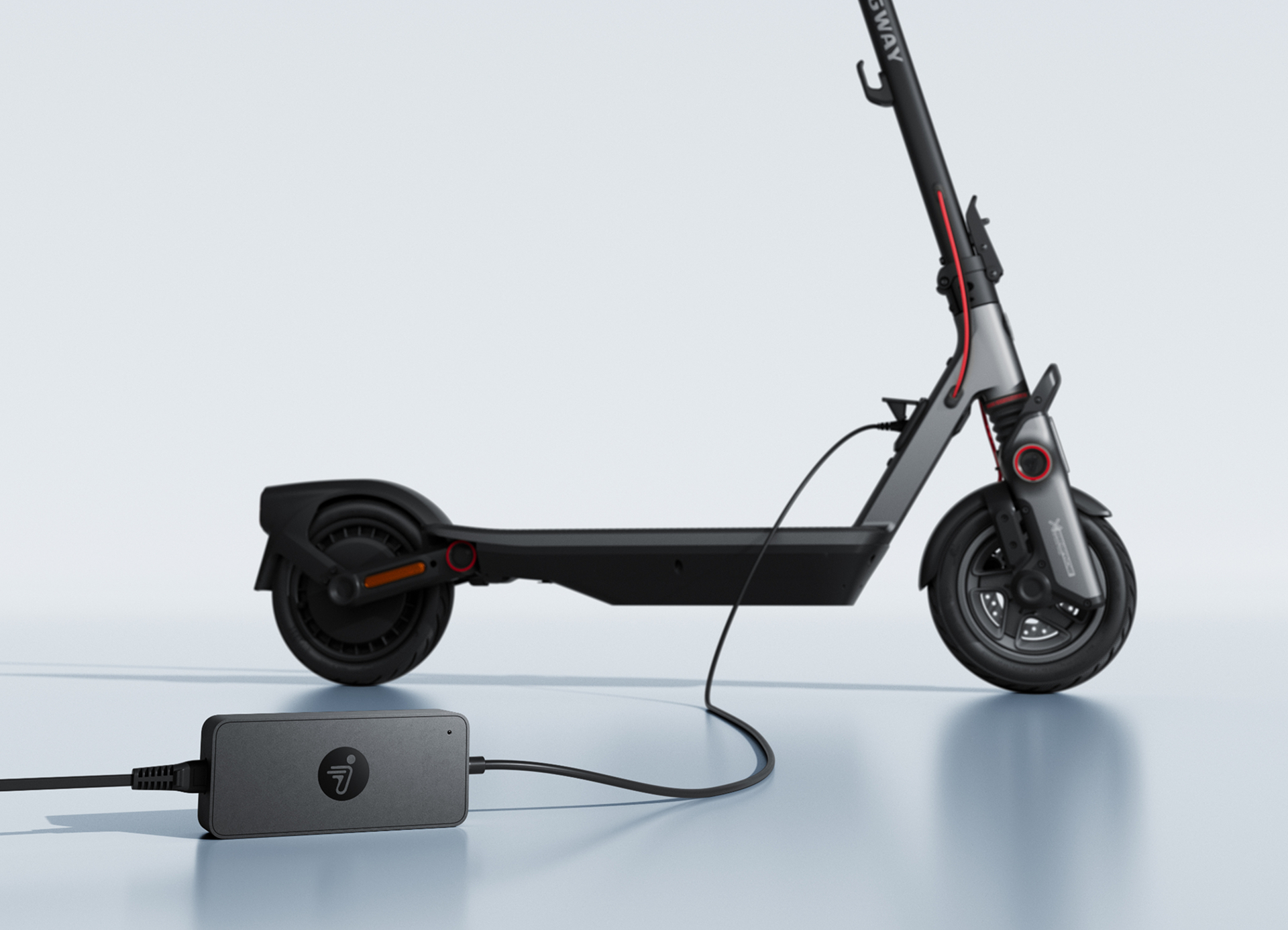 Ein Elektroroller wird geladen. Ein schwarzer Roller mit angeschlossenem Ladegerät. Der Hintergrund ist weiß.
