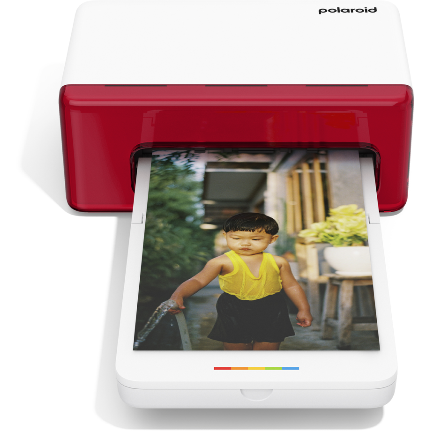 A Polaroid printer prints a photo of a child in yellow top and black shorts holding a water hose.