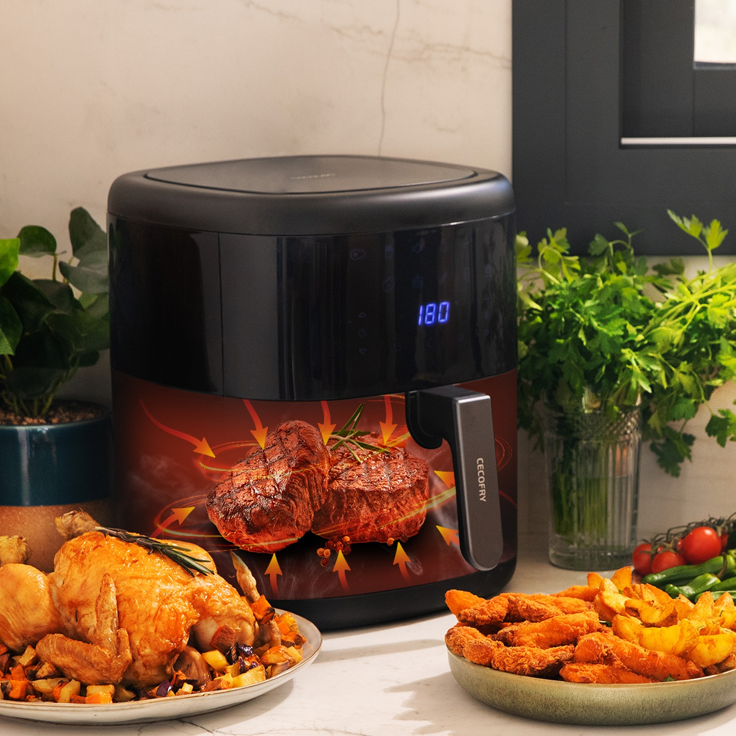 Una friggitrice ad aria con bistecche e un pollo arrosto su un tavolo. Patate e verdure sono vicine. La friggitrice mostra 180 gradi.