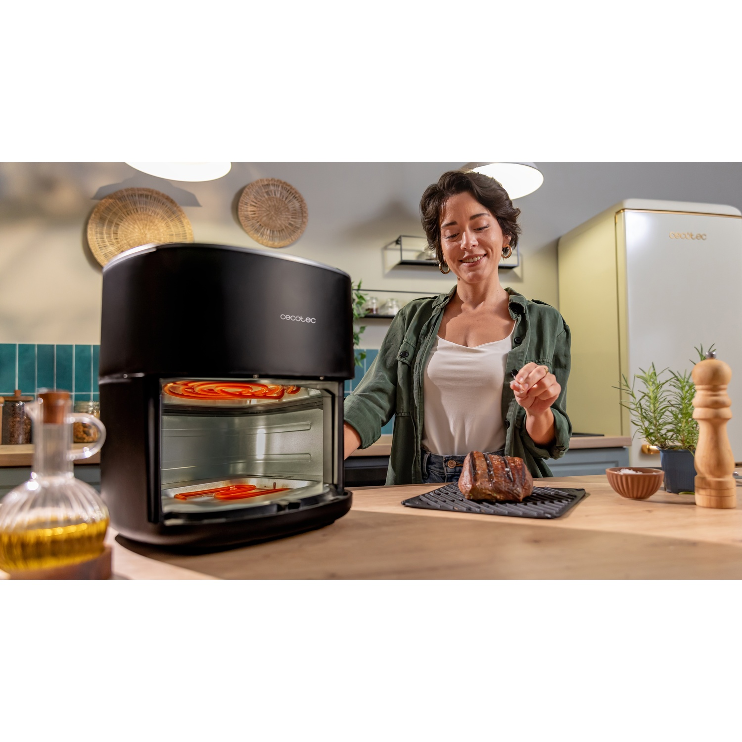 Donna in cucina con friggitrice ad aria. Bistecca sul bancone. Verdure all'interno dell'apparecchio. Sono visibili anche altri oggetti da cucina.