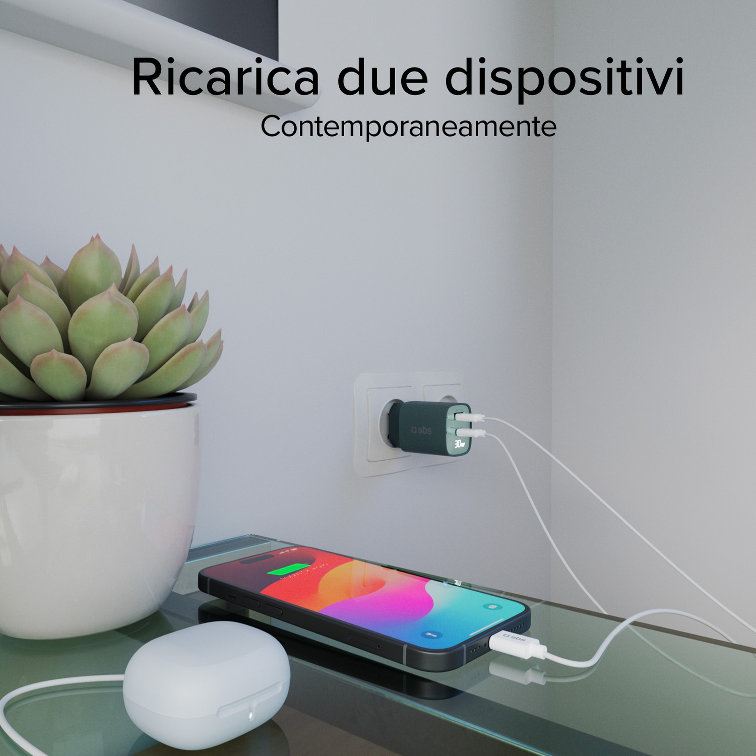 Un telefono e auricolari si caricano su una superficie di vetro. Un caricatore è collegato al muro. Una pianta è in un vaso bianco.