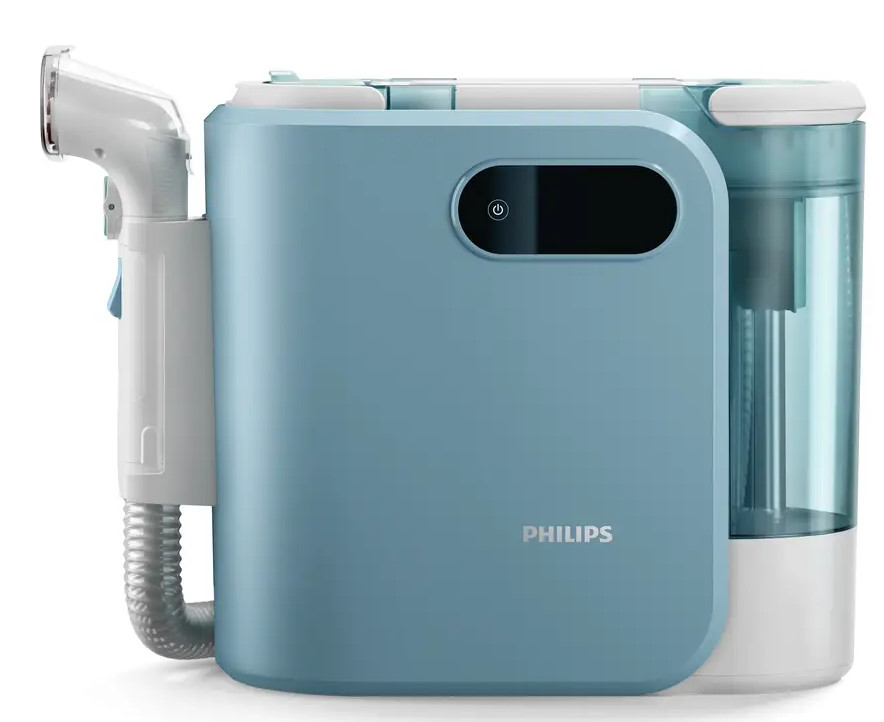 Niebiesko-białe urządzenie medyczne Philips. Posiada rurkę, przycisk zasilania i zbiornik na wodę. Urządzenie znajduje się na białej powierzchni.