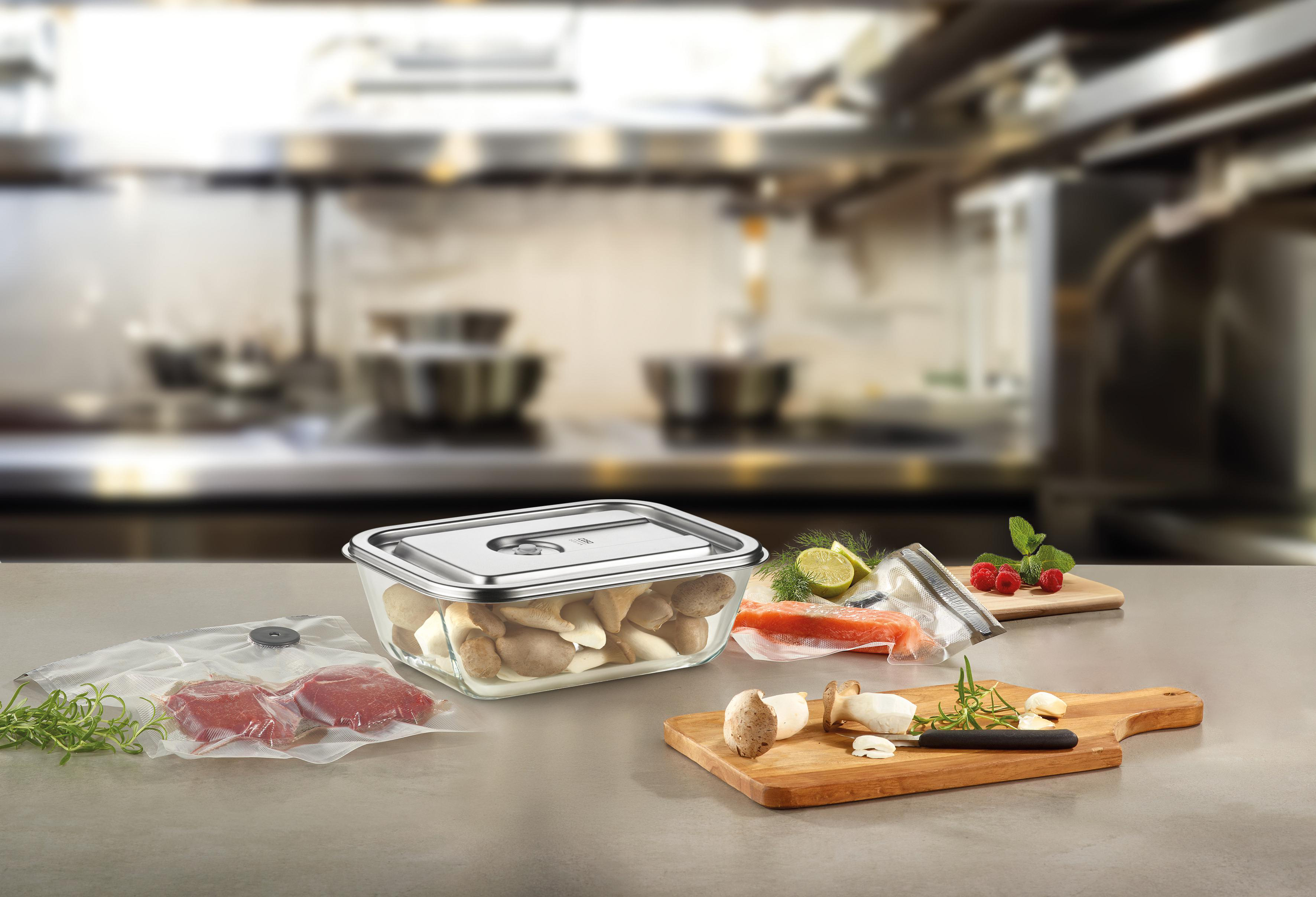 Eine Küchenszene mit Lebensmitteln: Pilze, Fleisch, Fisch und Himbeeren. Einige Artikel sind vakuumverpackt.