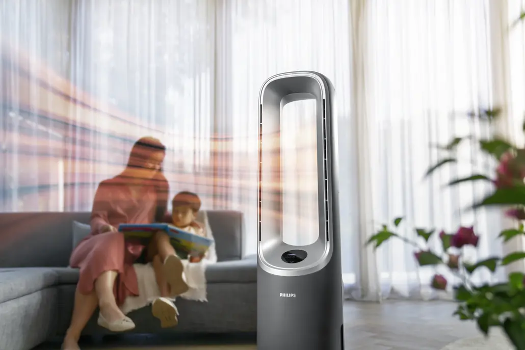 Eine Frau und ein Kind lesen auf einem Sofa, ein Philips-Ventilator steht im Vordergrund. Licht scheint daraus.