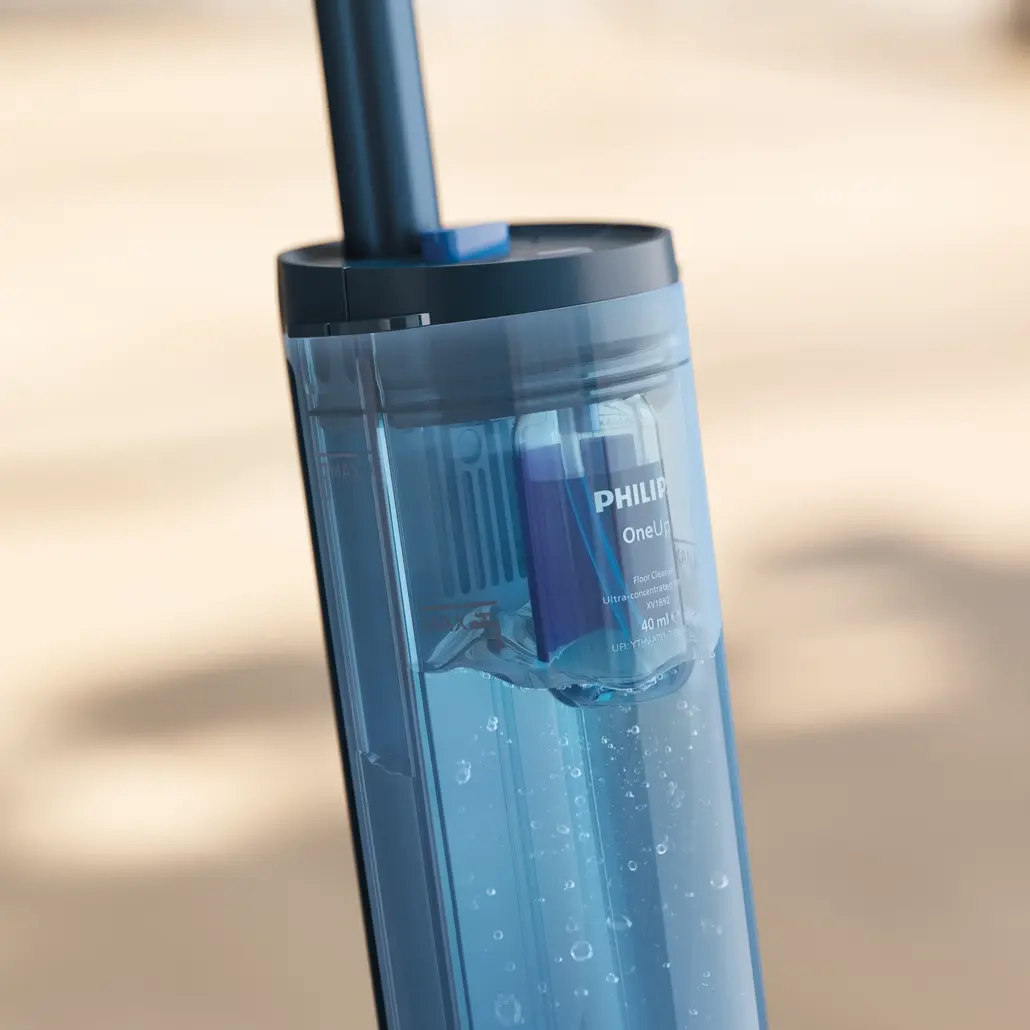 Nahaufnahme eines Philips OneUp Wassertanks, gefüllt mit blauer Flüssigkeit. Der Tank hat ein Etikett und einen dunkelblauen Griff. Blasen sind sichtbar.