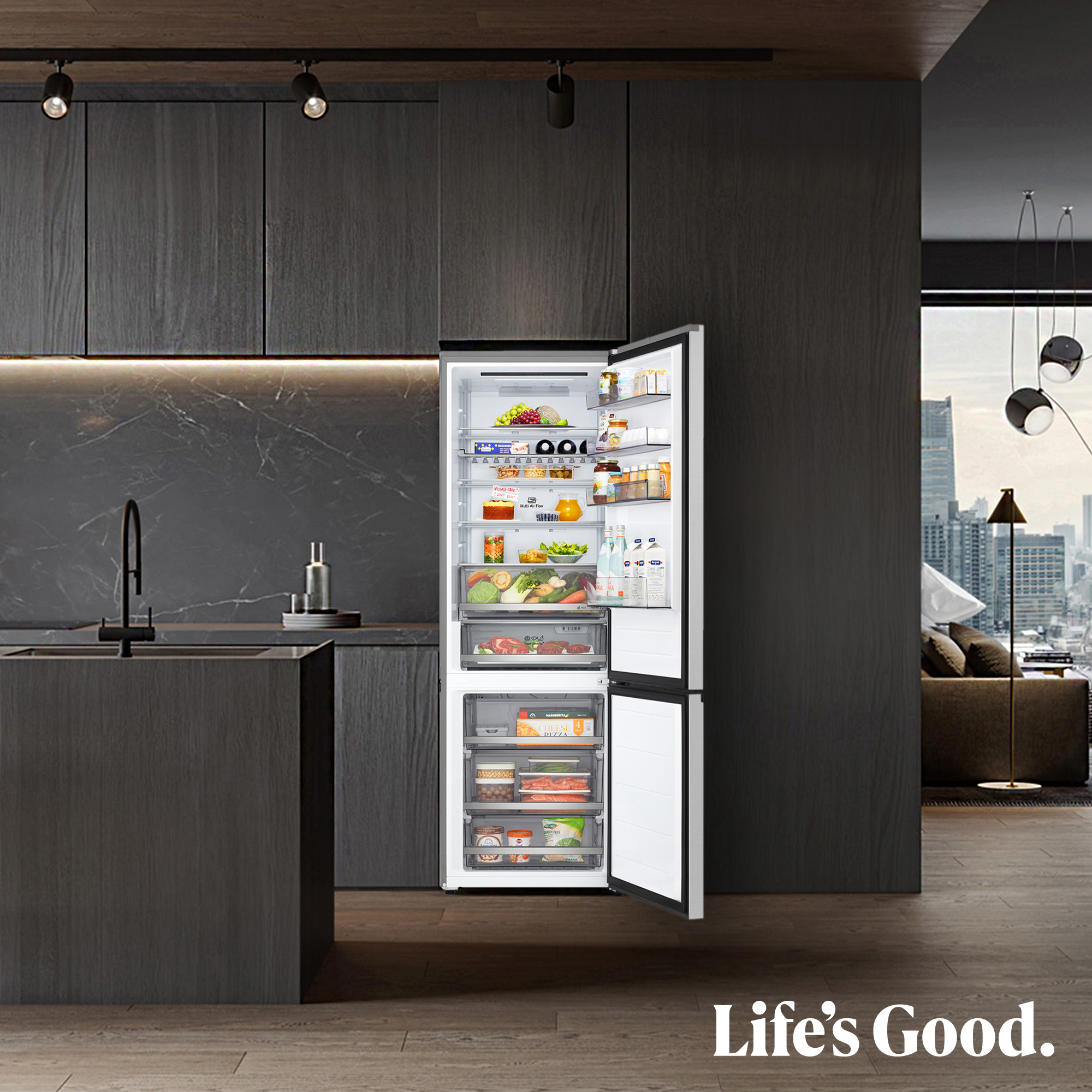Refrigerador abierto en una cocina moderna. Contiene alimentos. Gabinetes de madera oscura y vista de la ciudad en el fondo. Texto: Life's Good.