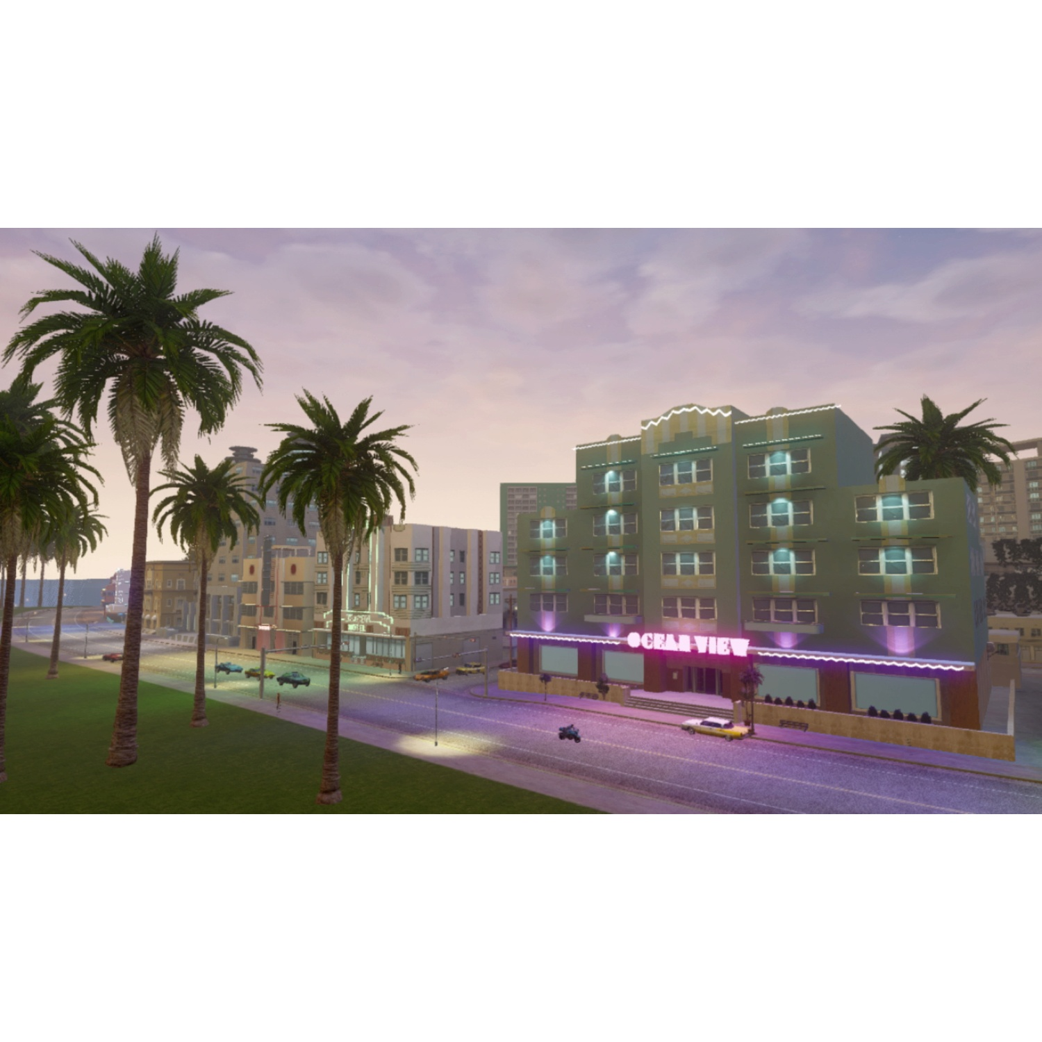 Palme costeggiano una strada con edifici, tra cui l'hotel Ocean View. Auto parcheggiate lungo la strada sotto un cielo al tramonto.