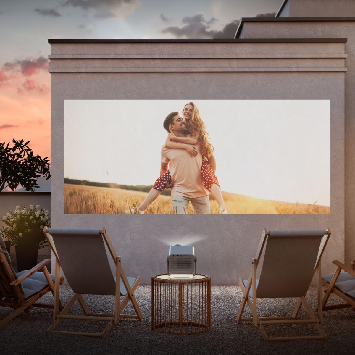 Projektor wyświetla obraz pary na ścianie. Dwa krzesła stoją przed ścianą. Niebo jest pomarańczowe.