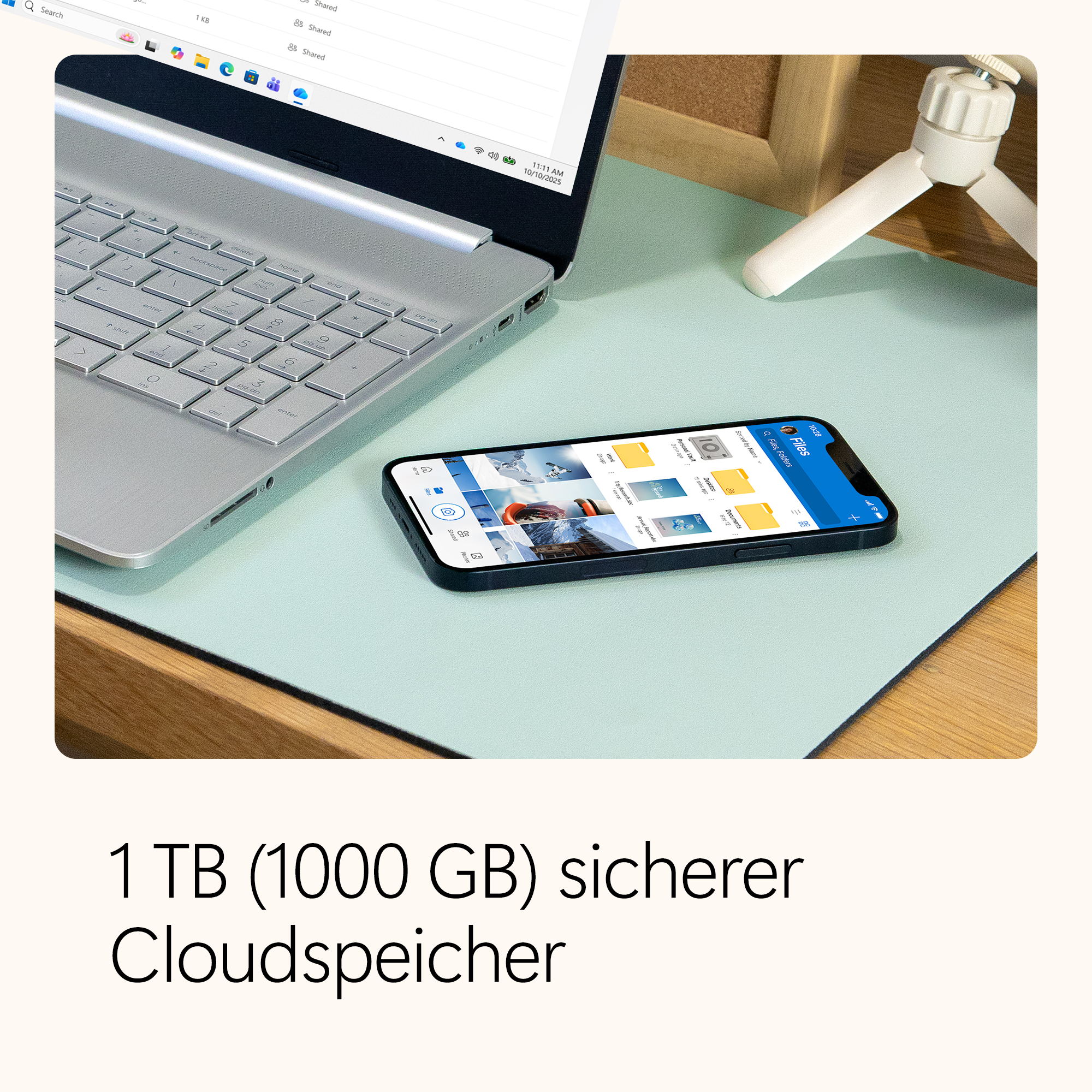 Laptop, Telefon und Stativ auf einem Schreibtisch. Das Telefon zeigt Dateien. Text unten: 1 TB sicherer Cloud-Speicher.