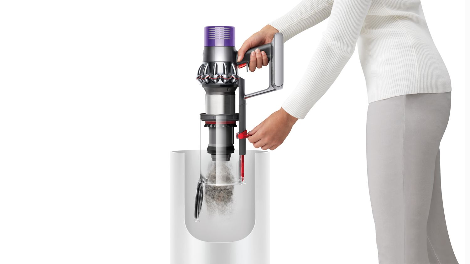 Bir kişi, toz toplama işlemini gösteren bir Dyson elektrikli süpürgesini tutuyor. Elektrikli süpürge gri ve mor renkte. Kişi beyaz ve gri giyiyor.