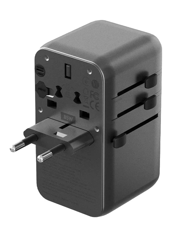 Czarny adapter podróżny z wieloma typami wtyczek. Ma przedłużoną wtyczkę UE i suwaki regulacyjne. Urządzenie jest na białym tle.