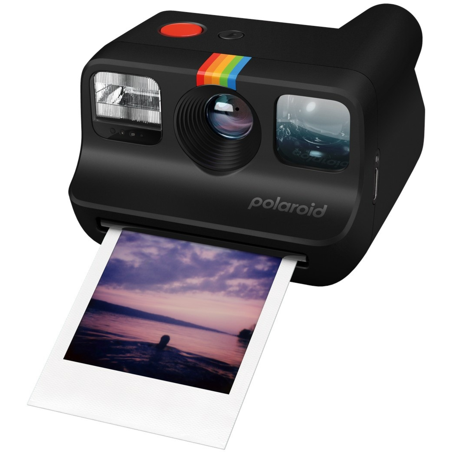 Appareil photo Polaroid noir imprimant une photo d'un coucher de soleil. L'appareil a une bande arc-en-ciel et un bouton rouge.