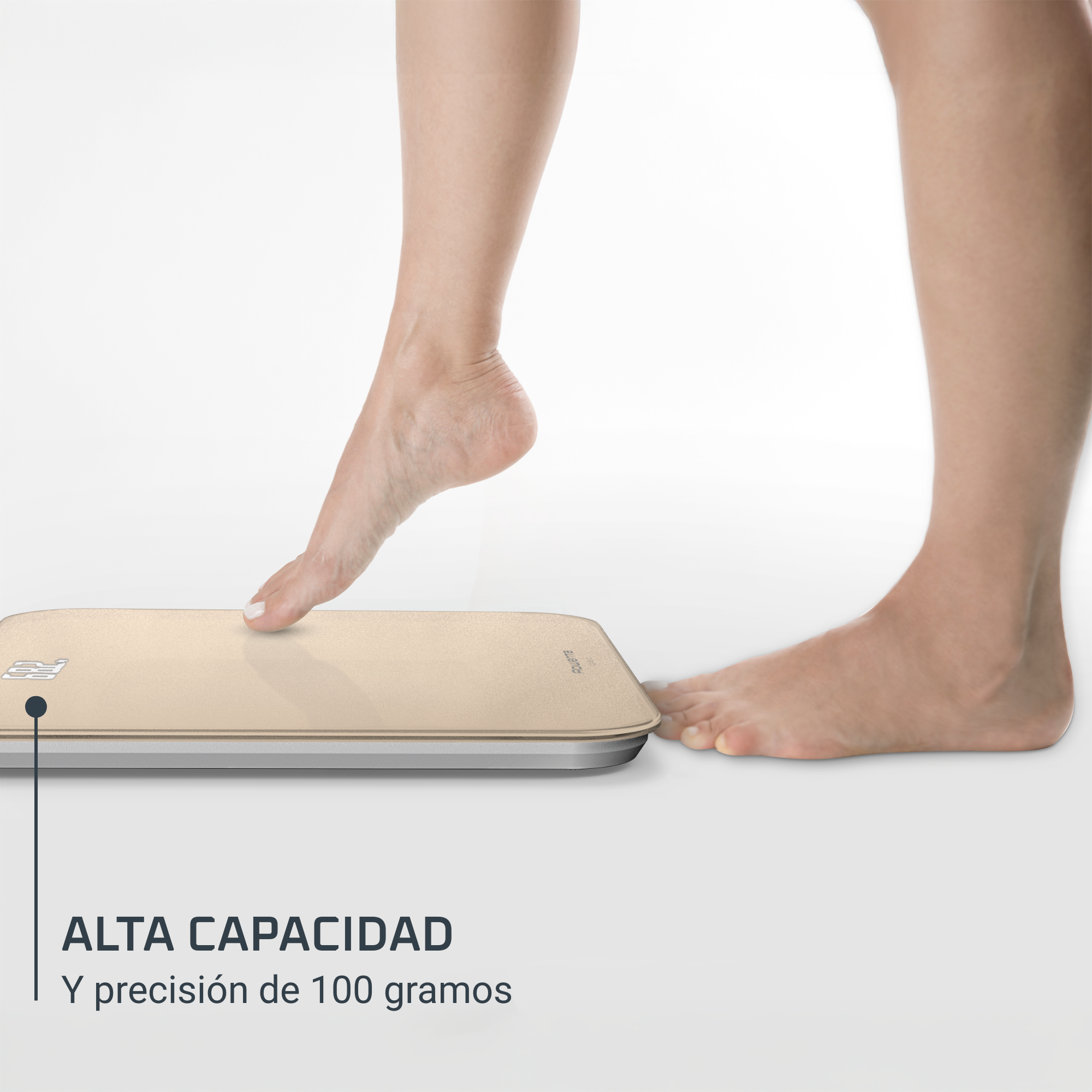 Un pie pisando una báscula dorada. La báscula está sobre una superficie blanca. El texto de abajo dice 'Alta capacidad'.