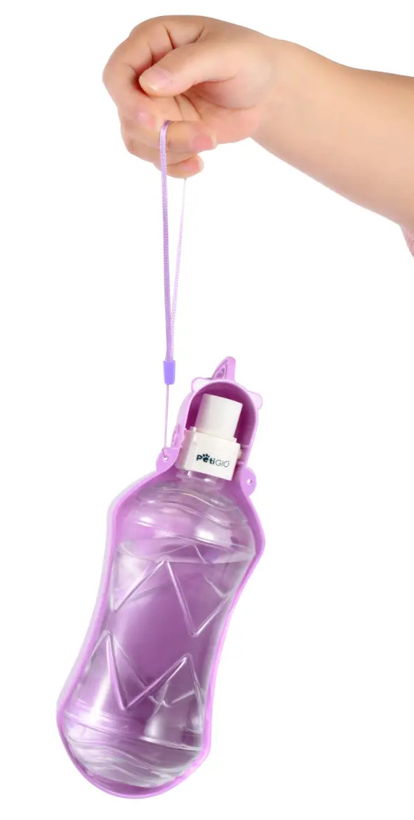 Ręka trzyma fioletową butelkę z wodą dla zwierząt. Butelka jest wypełniona wodą. Białe tło.
