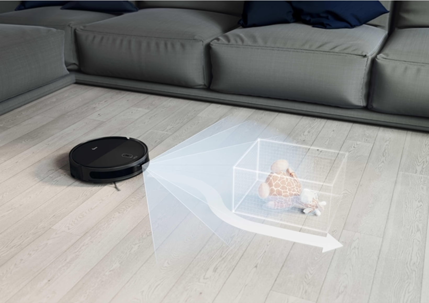 Un aspirateur robot noir sur un sol en bois, près d'un canapé gris. Une boîte virtuelle montre des jouets. Flèche indique le chemin de nettoyage.