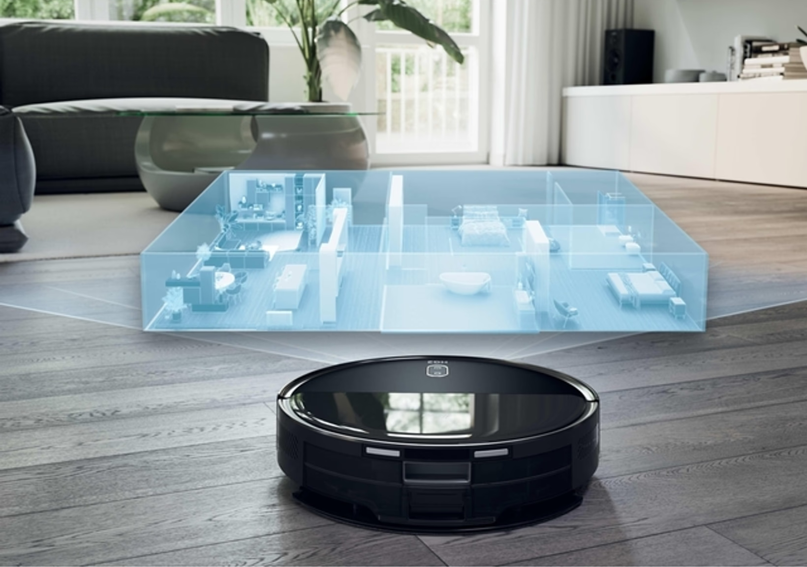 Un aspirateur robot noir sur un plancher en bois avec une superposition de plan de maison transparente bleue.