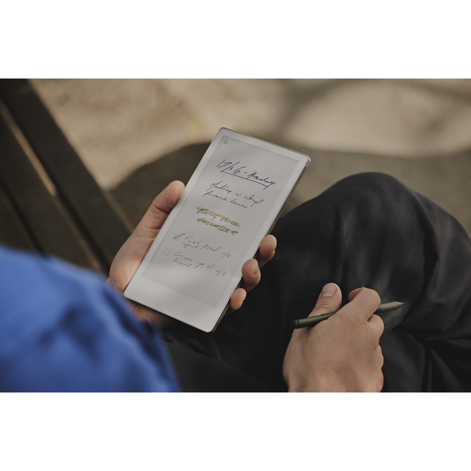 Een persoon die een tablet met handgeschreven notities vasthoudt. Een pen in de andere hand. De achtergrond is wazig.