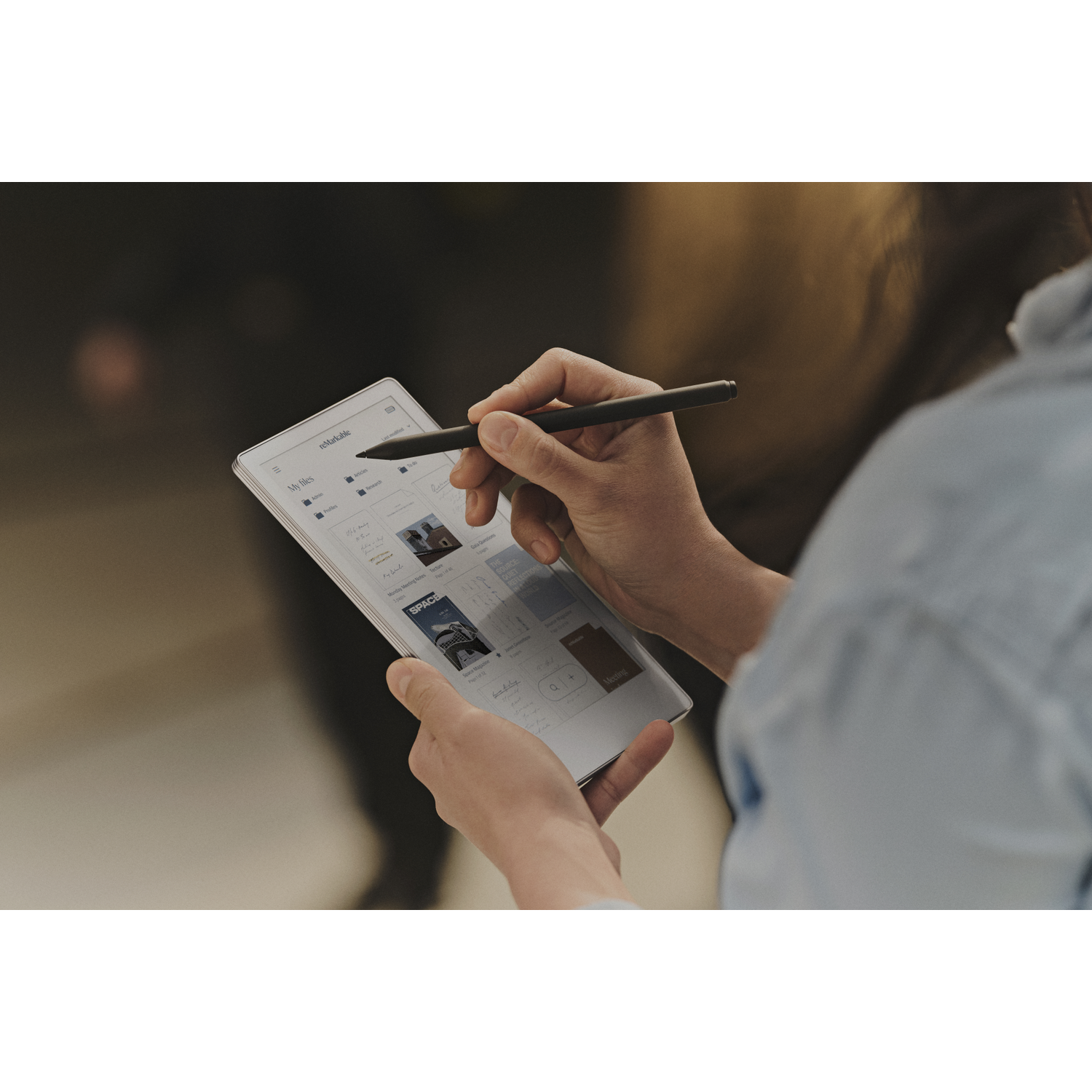 Een persoon gebruikt een digitale tablet met een stylus. Het scherm toont notities en documenten. De achtergrond is wazig.