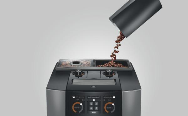 Kaffeebohnen gießen in eine Kaffeemaschine. Die Maschine ist schwarz und silber, mit Digitalanzeige.