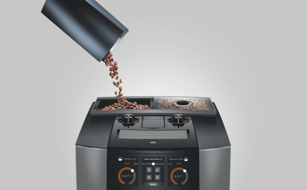 Kaffeebohnen werden in den Bohnenbehälter einer Kaffeemaschine gegossen. Die Maschine ist schwarz und silber, mit Digitalanzeige.