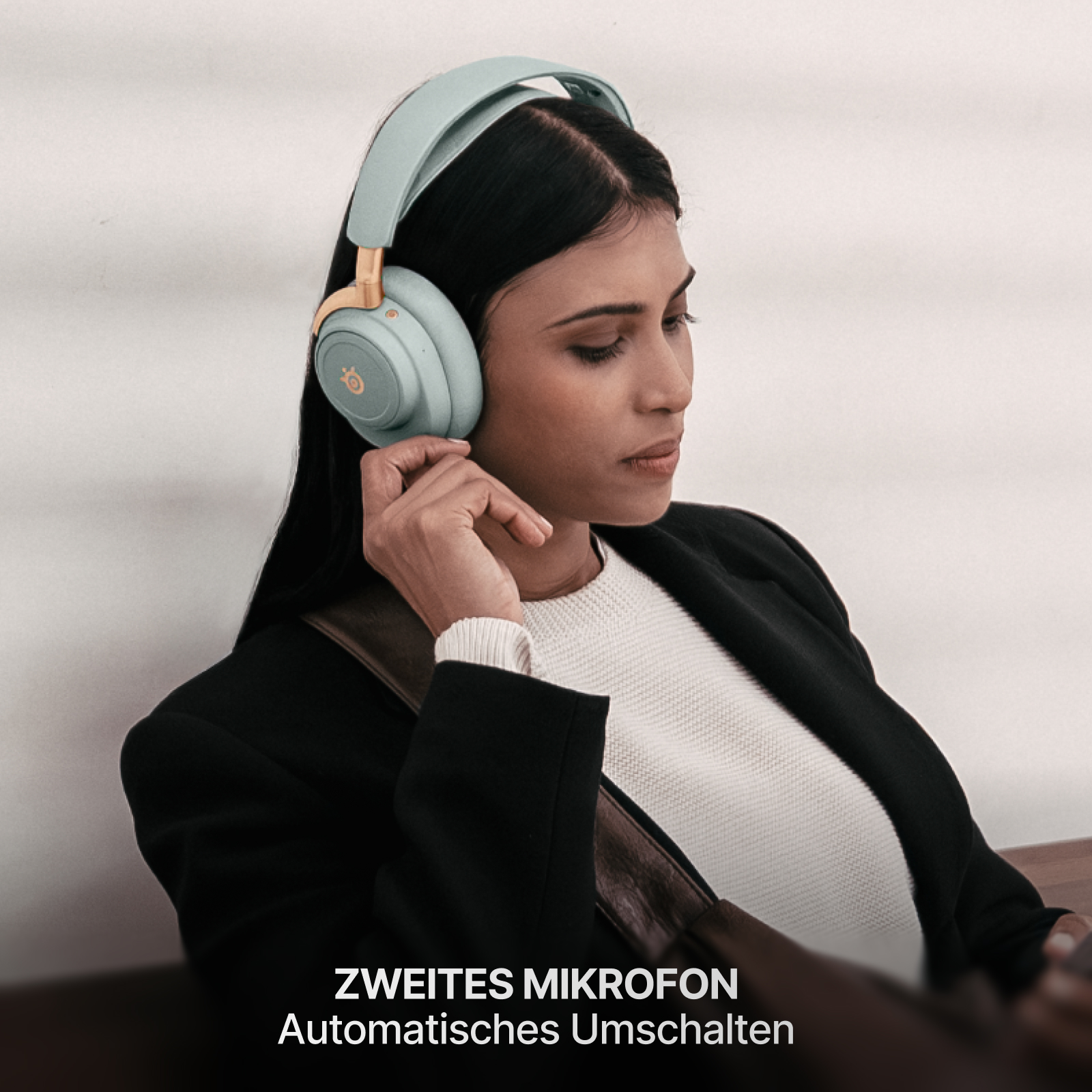 Frau mit mintfarbenen Kopfhörern, schwarzer Jacke, weißem Hemd. Text unten: Zweites Mikrofon, automatische Umschaltung.