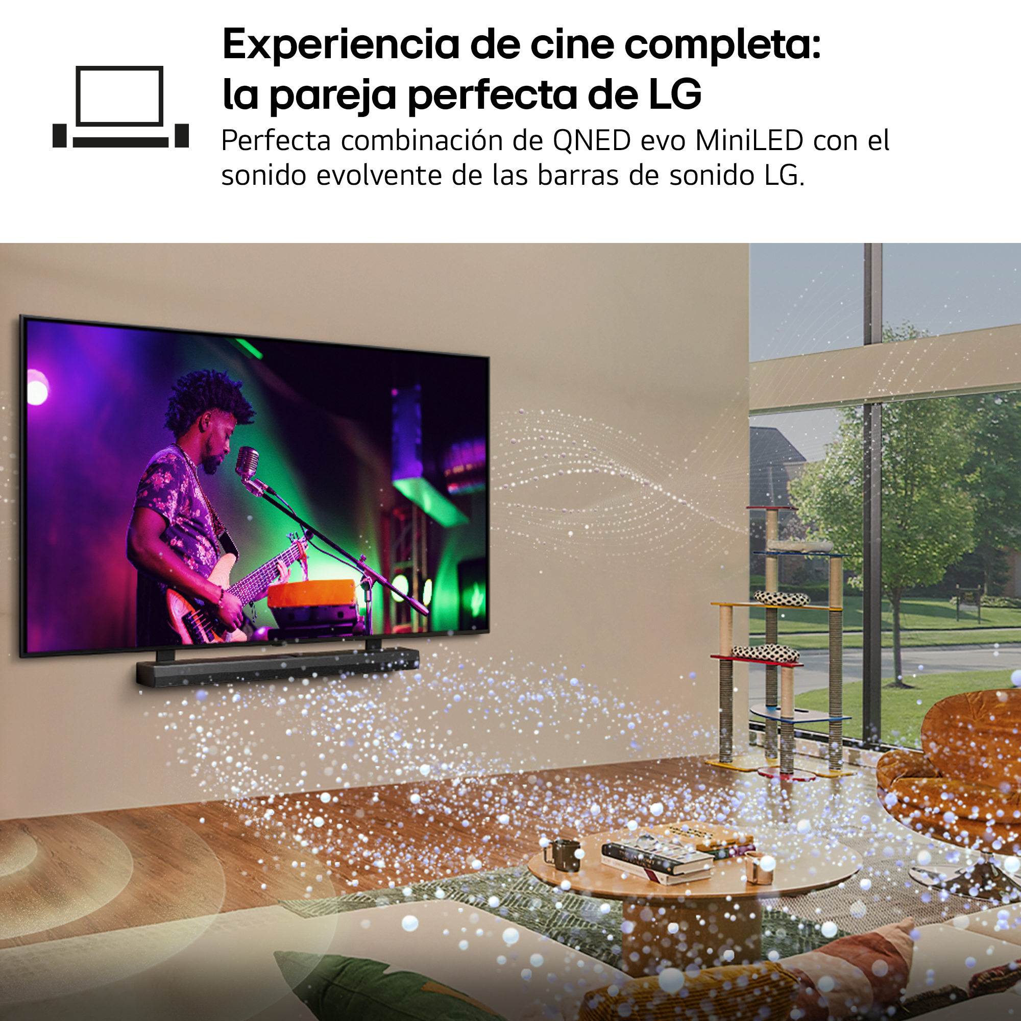 Un hombre toca la guitarra en la pantalla de un televisor. Debajo del televisor hay una barra de sonido. En el fondo hay un árbol para gatos y una silla.