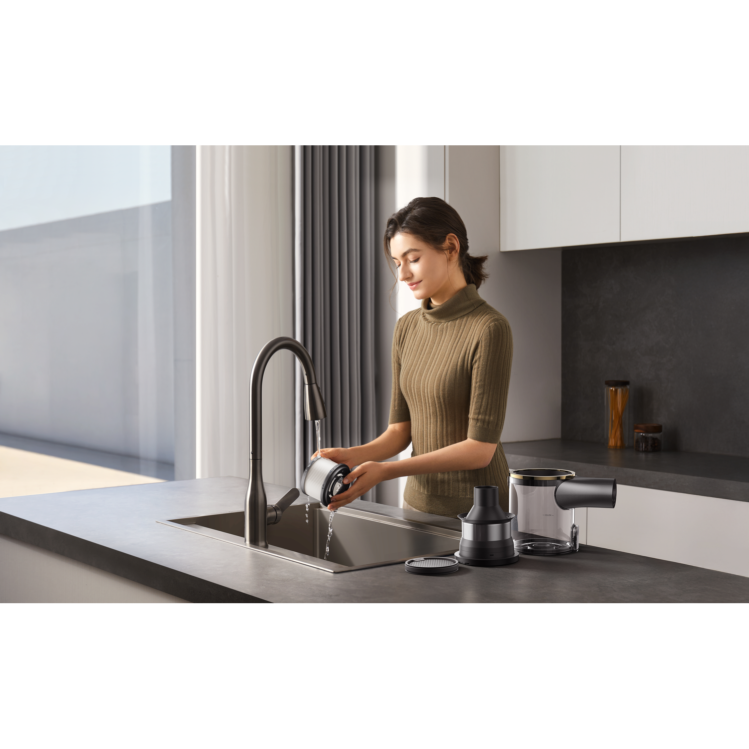 Een vrouw wast een filter onder stromend water in een gootsteen. Andere onderdelen van een apparaat liggen op het aanrecht.
