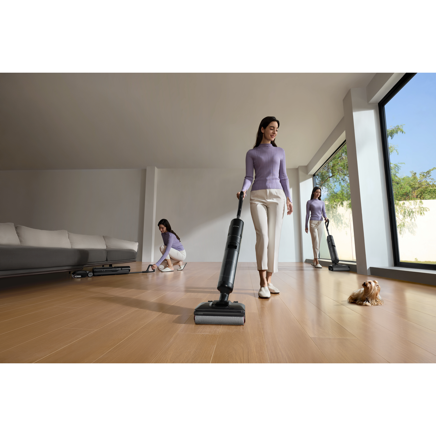 Trois femmes passent l'aspirateur dans une pièce. L'une se tient debout avec un aspirateur, une autre est à genoux et la troisième marche. Un petit chien se repose sur le sol.