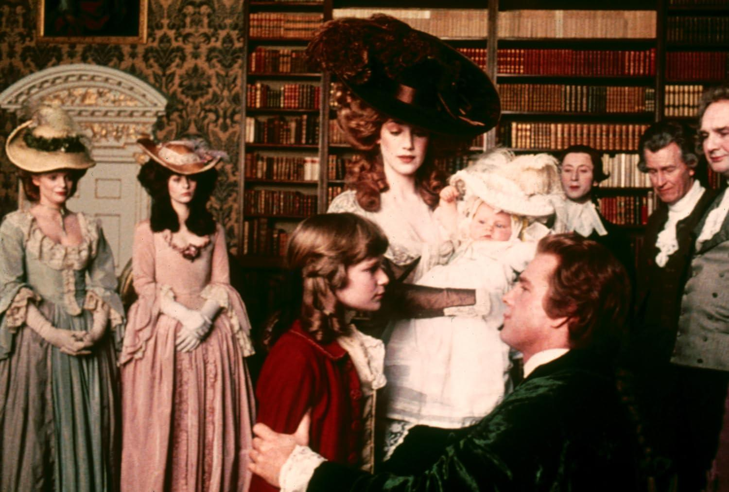 Gruppe von Menschen in historischer Kleidung, darunter Frauen in Kleidern und Hüten, versammelt in einer Bibliothek, mit einem Baby im Arm.