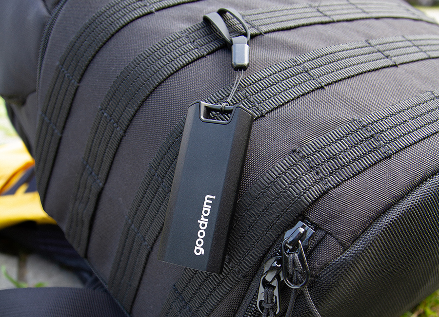 Czarny pendrive Goodram wisi na czarnym plecaku. Plecak ma czarne paski i zamek błyskawiczny.