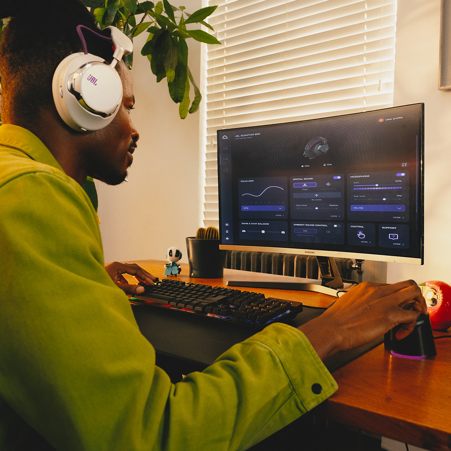 Een man met een JBL-headset gamet op een computer. Hij gebruikt een muis en een toetsenbord. Het scherm toont equalizerinstellingen.