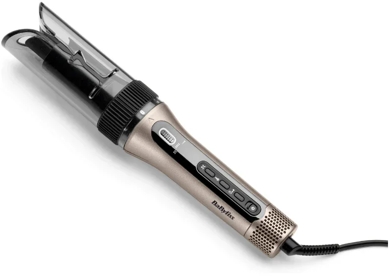 Un fer à friser Babyliss est posé sur une surface blanche. Il est doré et noir, avec des boutons et un couvercle en plastique transparent.