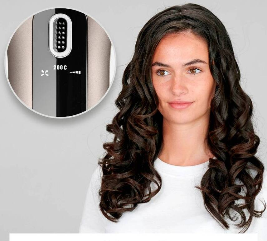 Une femme aux cheveux bouclés foncés. Un gros plan d'un fer à friser montre la température à 200°C. Elle porte une chemise blanche.