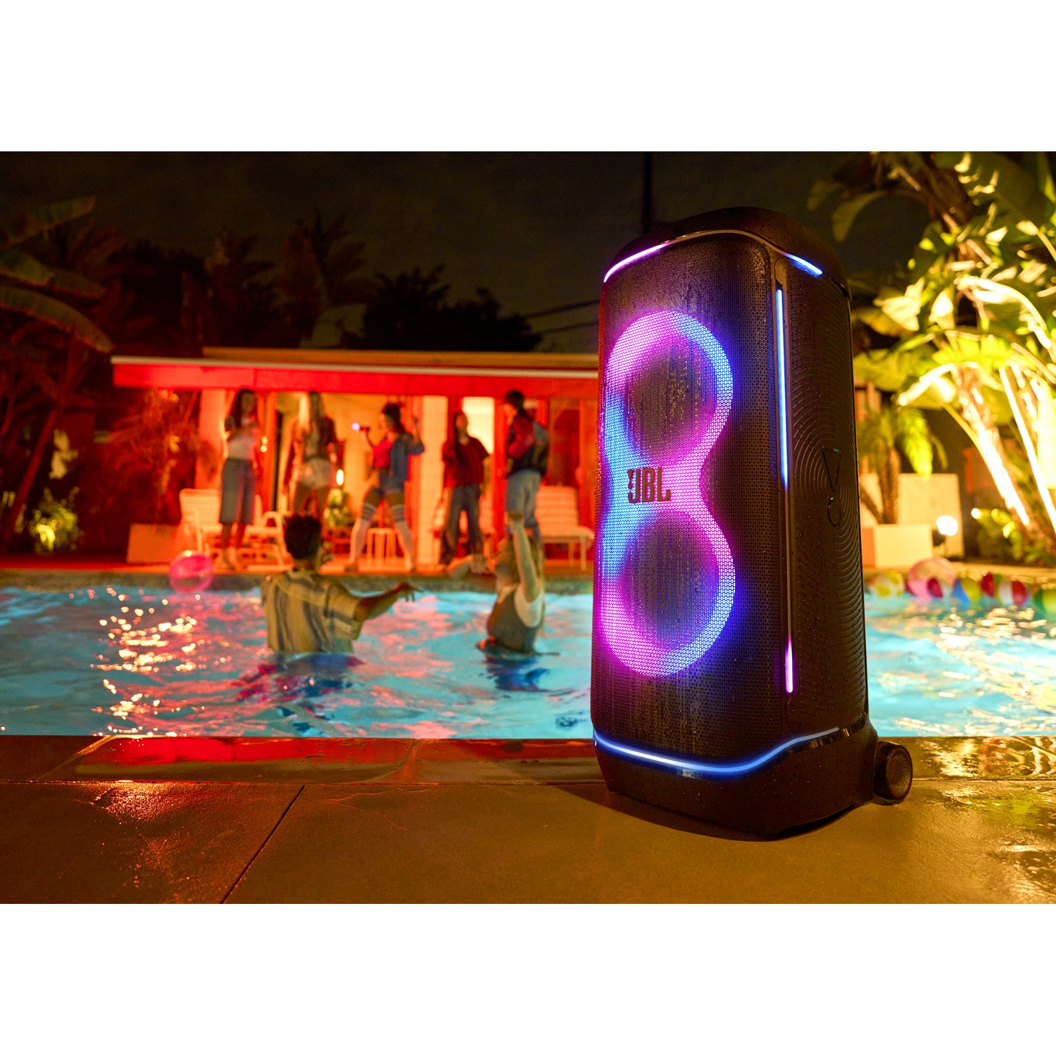 Een feestscène 's nachts met een zwembad. Mensen zijn in het water en eromheen. Een JBL-luidspreker staat aan de zijkant, verlicht.