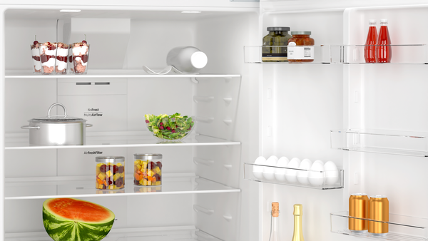 Açık bir buzdolabı, içinde tatlılar, kavanozlar, salata, karpuz, yumurta, içecekler ve tencereler var.