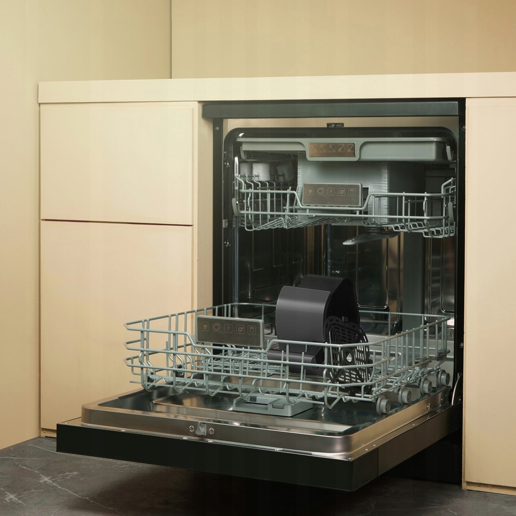 Otwarta zmywarka z koszami i czarną frytkownicą. Urządzenie jest wbudowane w jasną szafkę.