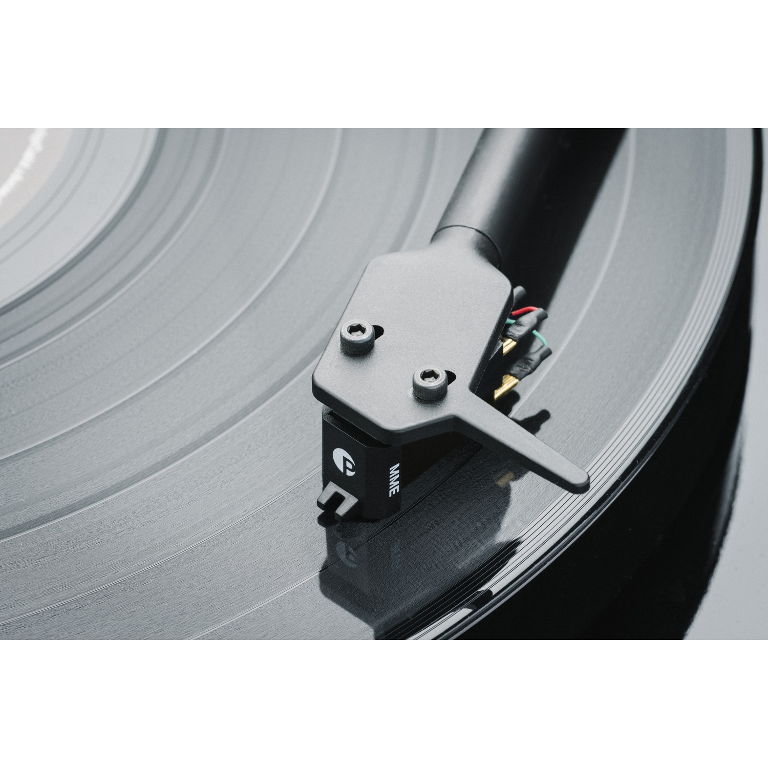 Primo piano di un giradischi. Il braccio nero è sopra un disco in vinile nero. L'ago è vicino al disco.