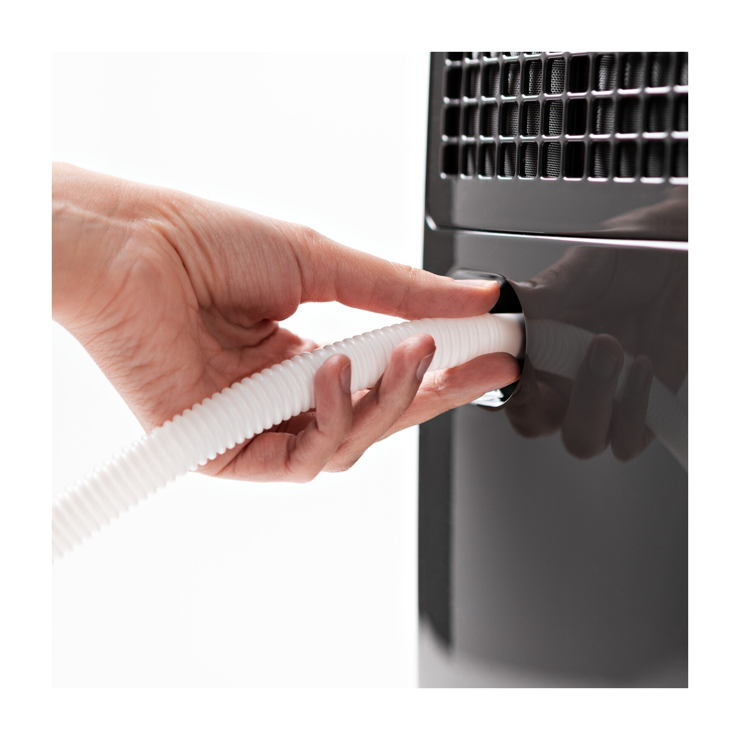 Una mano inserisce un tubo bianco e scanalato in una macchina grigio scuro. Lo sfondo è bianco.