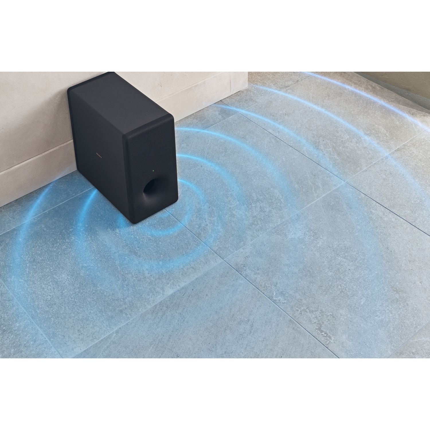 Un subwoofer nero vicino a un angolo. Linee blu di onde sonore emanano dall'altoparlante su un pavimento piastrellato.