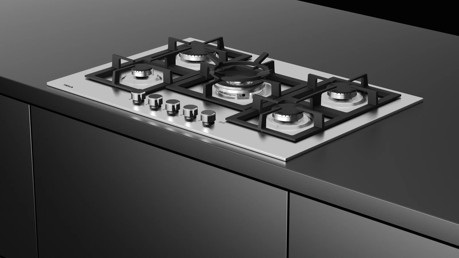 Stalowa płyta gazowa z czterema palnikami i pokrętłami. Widoczny czarny blat i szafki.