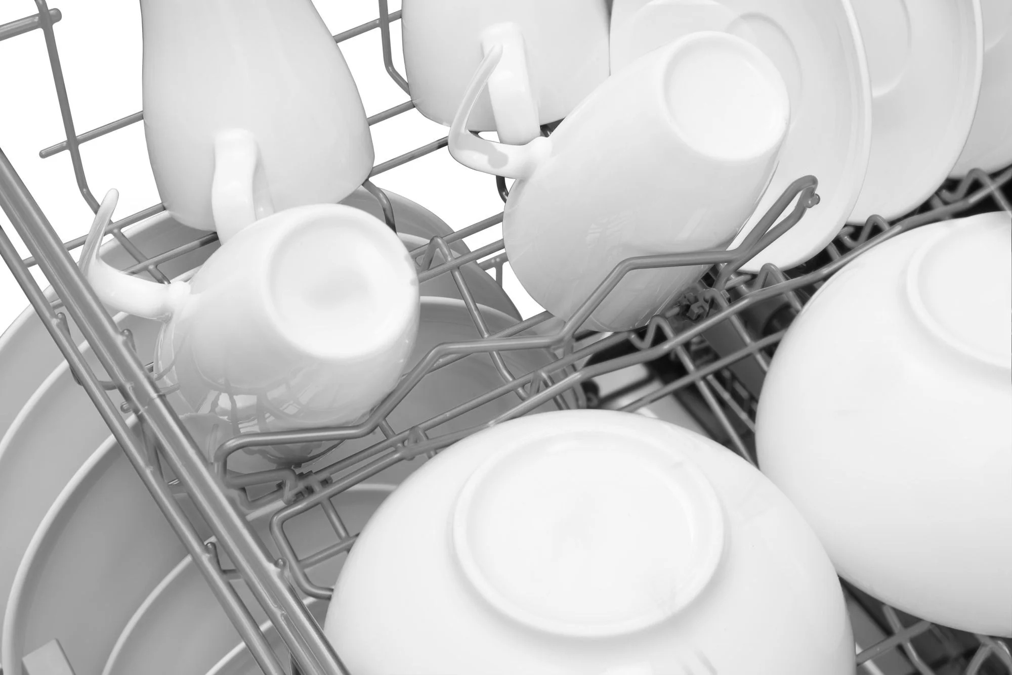 Stojak do zmywarki wypełniony białymi kubkami, miskami i talerzami. Naczynia są ułożone w stojaku, gotowe do mycia.
