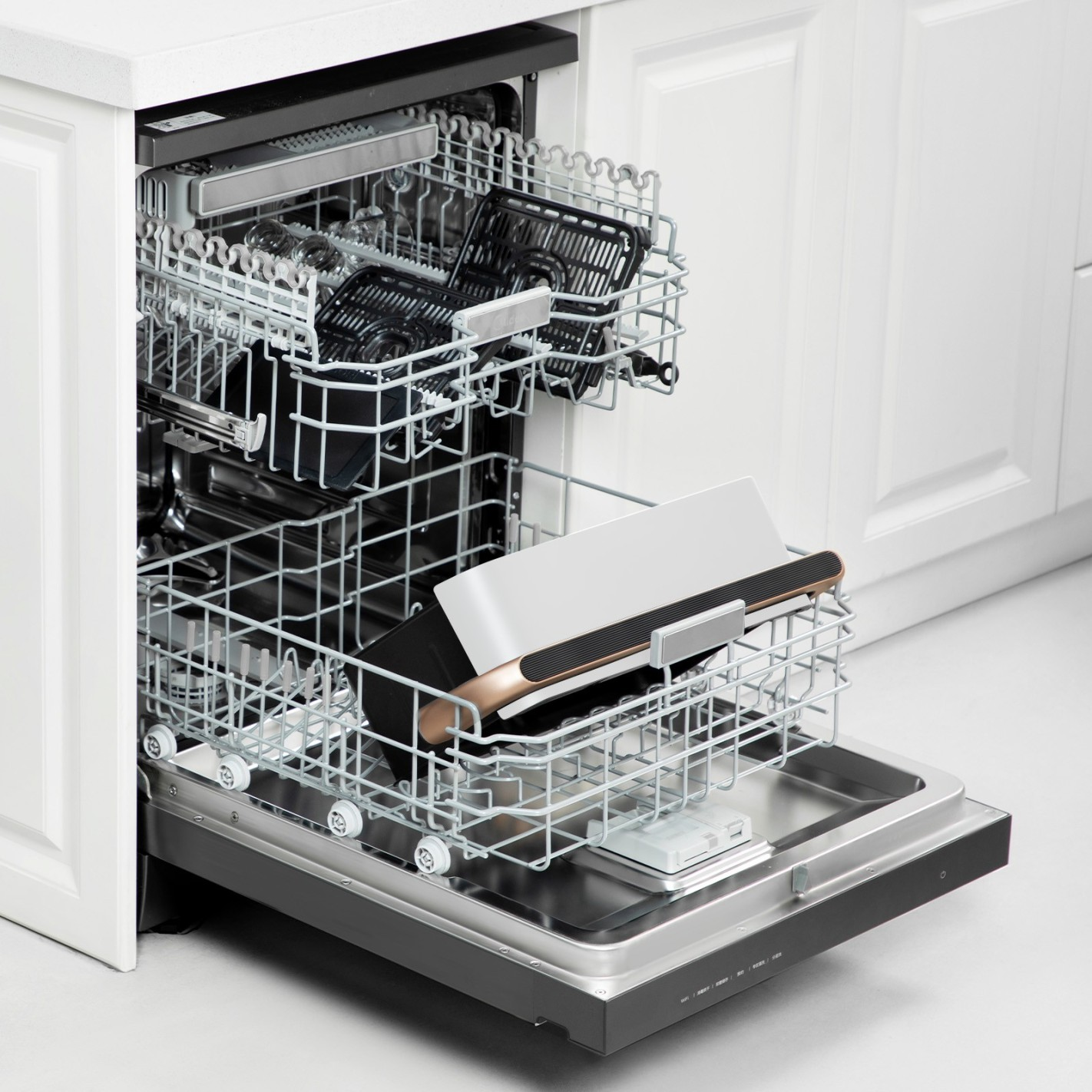 Otwarta zmywarka z naczyniami w środku. Zmywarka jest ze stali nierdzewnej z białymi szafkami w tle.