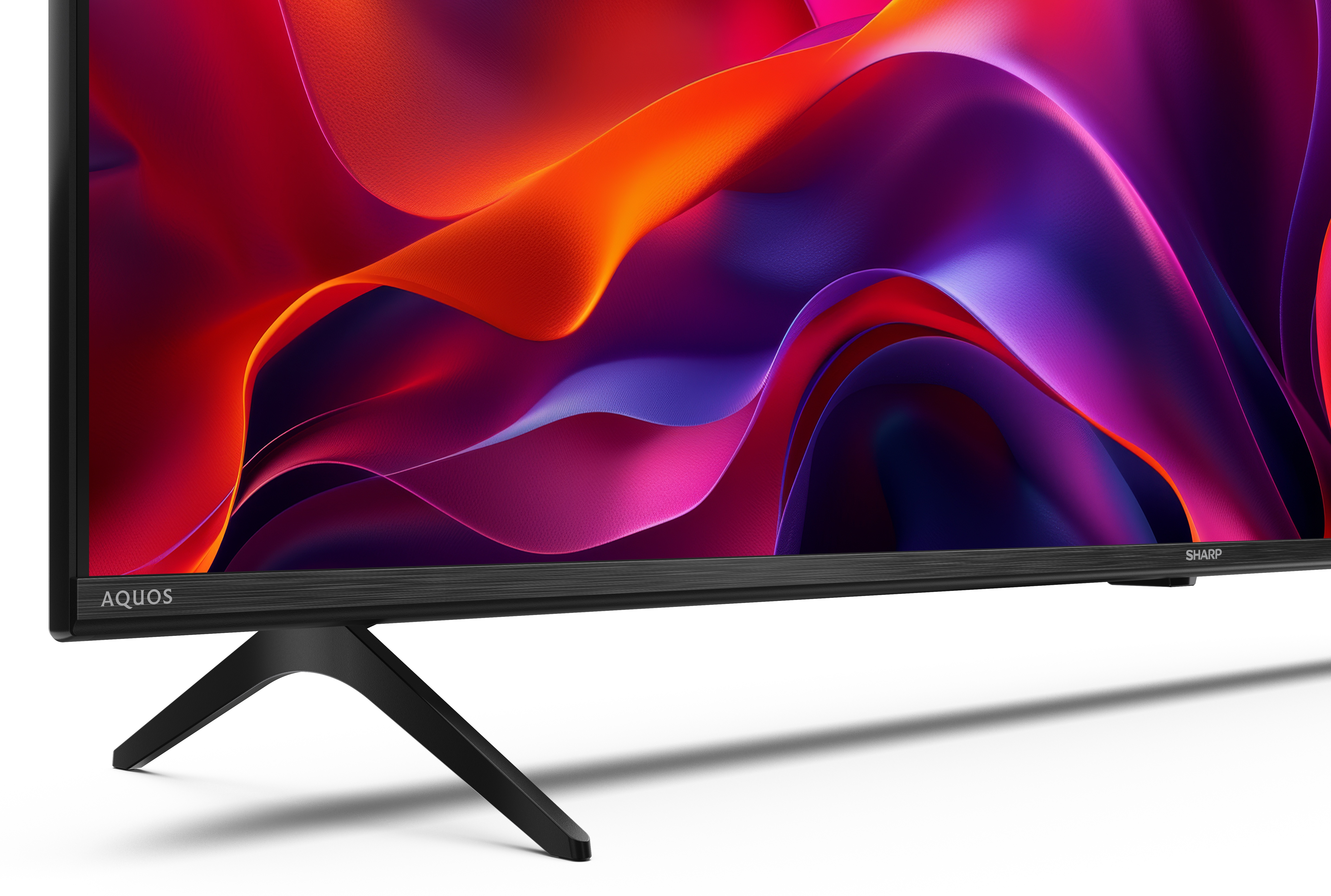 Czarny telewizor Sharp Aquos. Ekran wyświetla abstrakcyjne, kolorowe kształty. Telewizor stoi na czarnym stojaku.